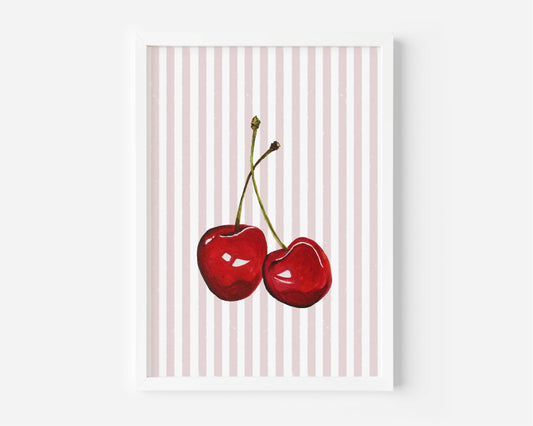 A framed art print featuring two glossy red cherries on a background of vertical light pink and white stripes, displayed against a clean white wall.