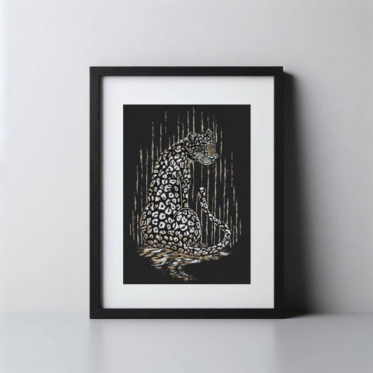 A framed art print featuring a detailed black and white leopard illustration with gold accents, set in a black frame with a white mat against a light gray wall.