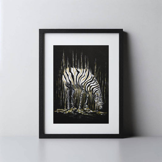 A framed art print featuring a black and white zebra illustration against a dark background with vertical gold-toned brushstrokes, shown in a black frame with a white mat on a light gray wall and surface.