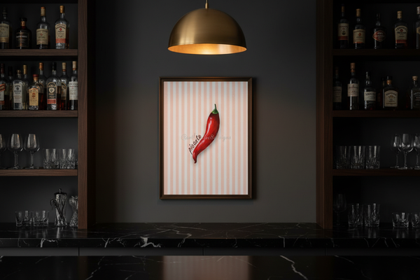 A framed wall art print featuring a single red chili pepper on a white striped background, hanging on a dark gray wall in a bar setting with shelves of bottles and glasses.