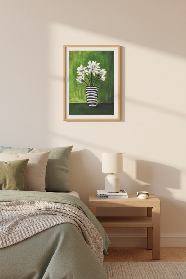 A framed art print depicting white flowers in a striped vase against a green background, hanging on a beige wall above a bed in a styled bedroom.