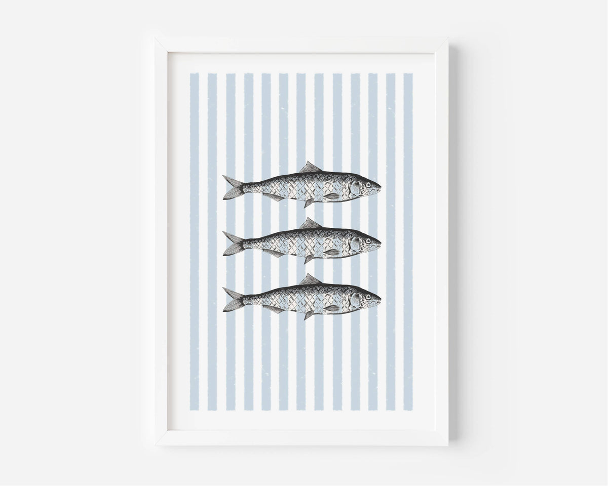 A framed art print featuring three horizontal fish illustrations over vertical light blue and white stripes, displayed in a white frame against a light gray wall.