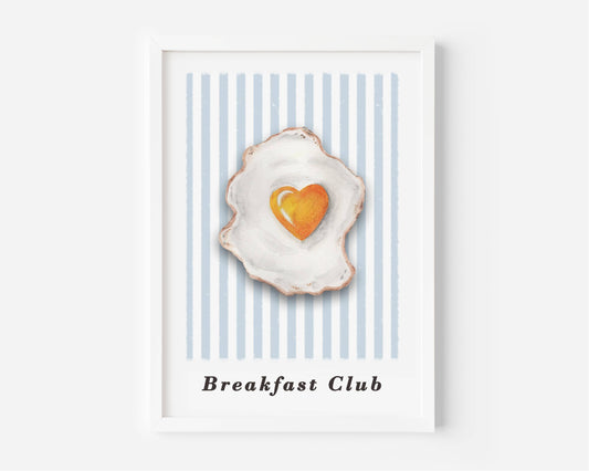 A framed art print featuring a watercolor-style fried egg with a heart-shaped yellow yolk on a background of light blue and white vertical stripes, with the text 'Breakfast Club' printed below.