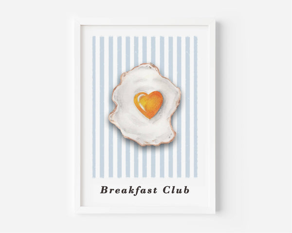 A framed art print featuring a watercolor-style fried egg with a heart-shaped yellow yolk on a background of light blue and white vertical stripes, with the text 'Breakfast Club' printed below.