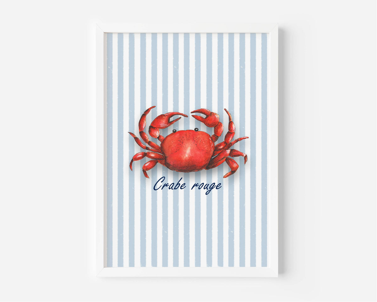 A framed nautical art print featuring a red crab on a background of light blue and white vertical stripes, with the French text 'Crabe rouge' written below in navy blue script. The print is housed in a clean white frame and is displayed against a neutral light gray wall.