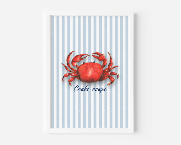 A framed nautical art print featuring a red crab on a background of light blue and white vertical stripes, with the French text 'Crabe rouge' written below in navy blue script. The print is housed in a clean white frame and is displayed against a neutral light gray wall.