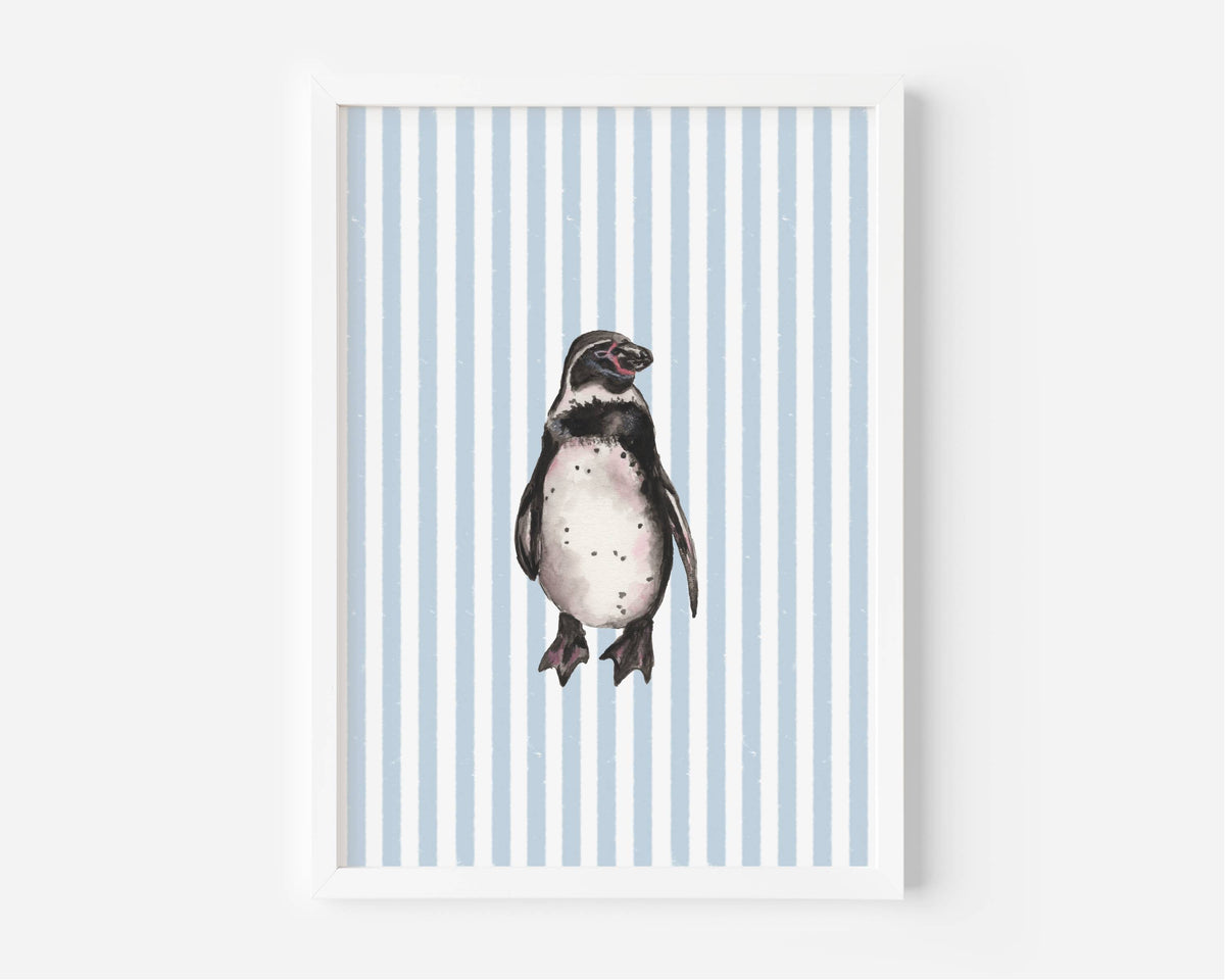 A framed art print featuring a watercolor illustration of a penguin centered on a background of light blue and white vertical stripes, displayed against a clean white wall.