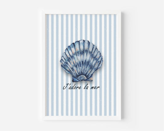 A framed wall art print featuring a blue scallop shell illustration centered on a white and light blue striped background, with the French text 'J'adore la mer' below. The print is shown in a white frame against a light gray wall.