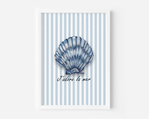 A framed wall art print featuring a blue scallop shell illustration centered on a white and light blue striped background, with the French text 'J'adore la mer' below. The print is shown in a white frame against a light gray wall.