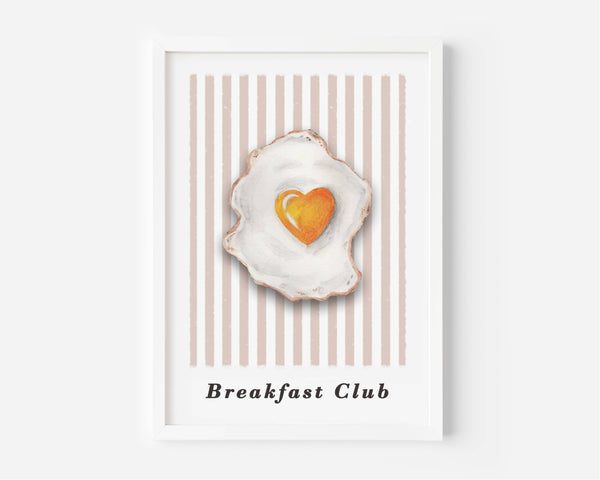 A framed art print featuring a watercolor-style fried egg with a heart-shaped yellow yolk, set against a background of vertical beige and white stripes. The text 'Breakfast Club' is printed at the bottom.
