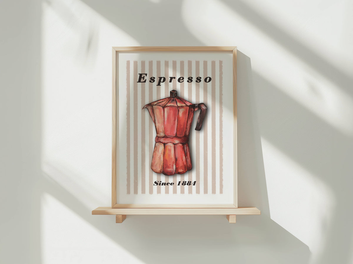 A framed art print featuring a vintage red espresso moka pot on a cream striped background with the text 'Espresso' and 'Since 1881', displayed on a small wooden stand against a white wall with soft window shadows.