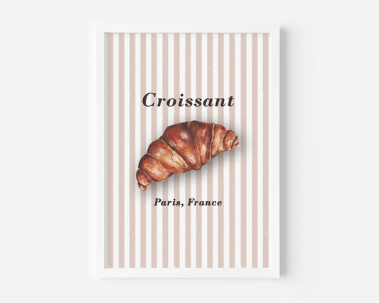 A framed wall art print featuring a croissant illustration over vertical beige and white stripes, with the word 'Croissant' and 'Paris, France' printed on the artwork.