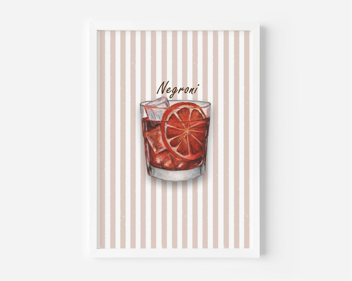 A framed art print featuring a watercolour illustration of a Negroni cocktail in a tumbler glass with ice and an orange slice garnish, set against a background of vertical beige and white stripes. The print is shown in a white frame against a light grey wall.