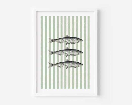 Framed wall art featuring three horizontal fish illustrations centered on a background of vertical sage green and white stripes, shown in a white frame against a light gray wall.