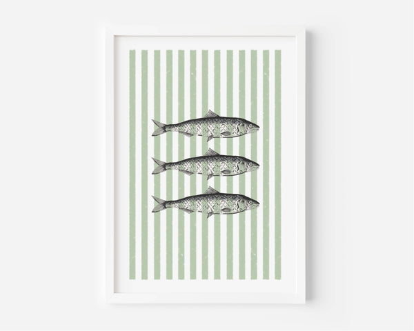 Framed wall art featuring three horizontal fish illustrations centered on a background of vertical sage green and white stripes, shown in a white frame against a light gray wall.