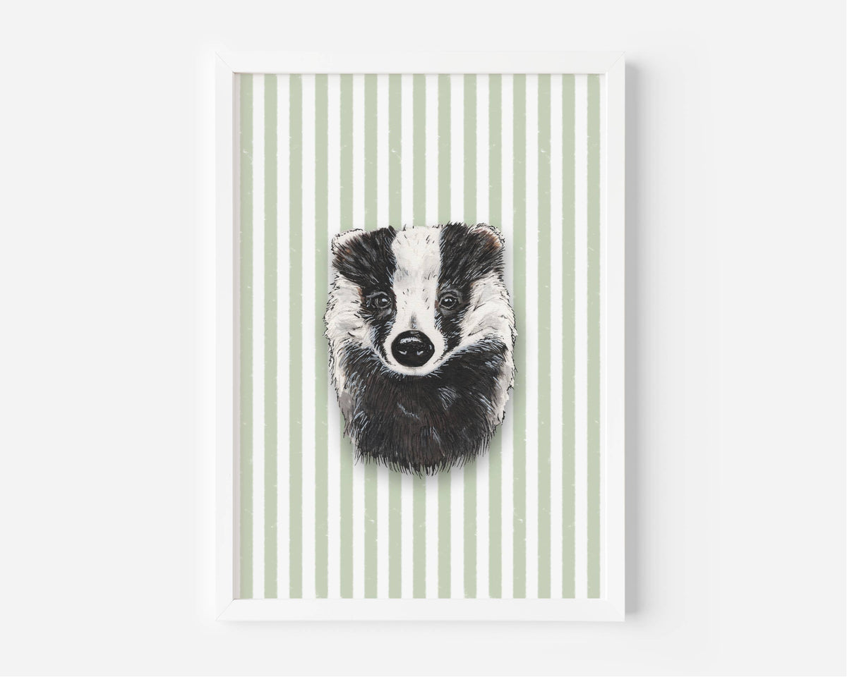 A framed art print featuring a black and white sketch of a badger's face centered on a background of vertical sage green and white stripes, displayed on a clean white wall.