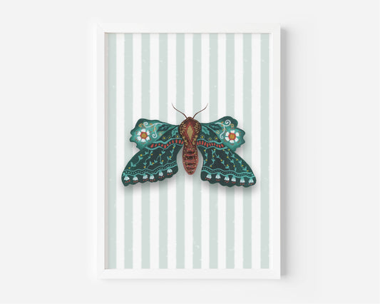 A framed art print featuring a detailed teal and brown moth with orange accents on a background of pale mint green and white vertical stripes, set against a clean white wall.