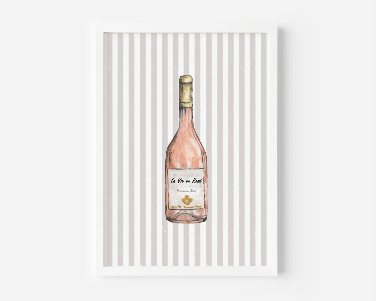 A framed art print featuring a watercolor illustration of a pink wine bottle against a background of vertical gray and white stripes, displayed on a clean white wall.