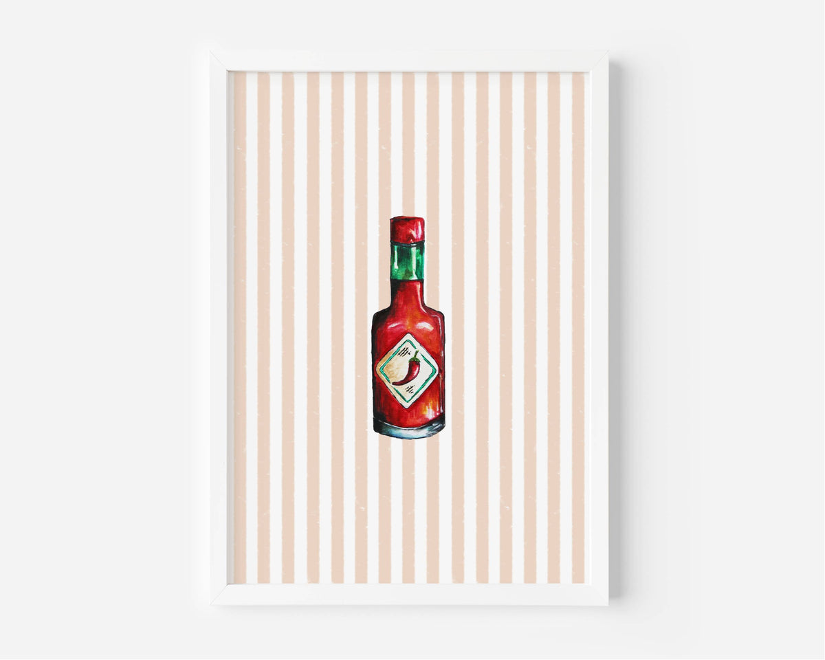 A framed art print featuring a watercolor-style illustration of a red hot sauce bottle centered on a background of vertical peach and white stripes, set against a clean white wall.