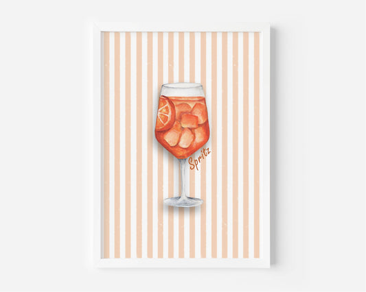 A framed art print featuring a watercolor illustration of a glass of orange soda with ice and a lemon slice, set against a background of vertical peach and white stripes. The print is housed in a simple white frame and is displayed against a neutral light gray wall.