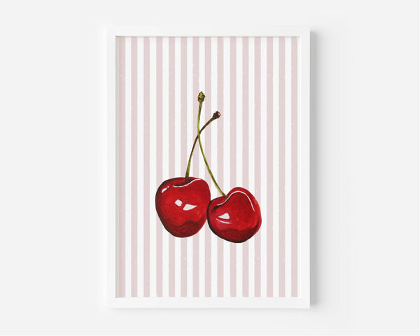 A framed art print featuring two glossy red cherries on a background of vertical light pink and white stripes, displayed against a clean white wall.