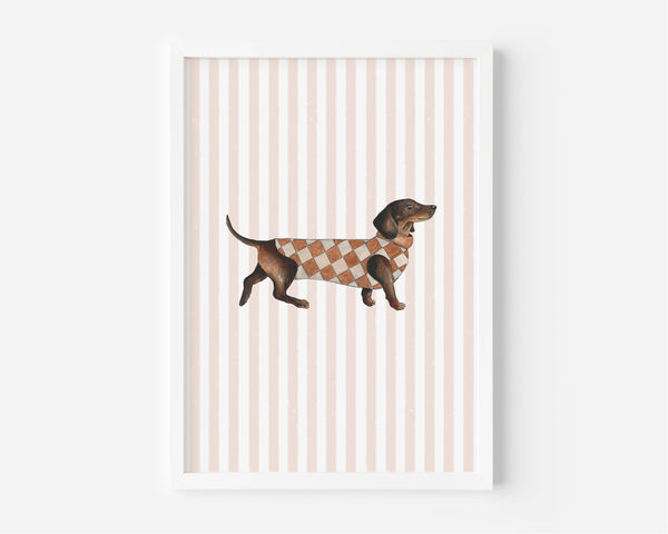 A framed art print featuring a brown dachshund wearing a brown and beige argyle sweater, set against a background of vertical light pink and white stripes.