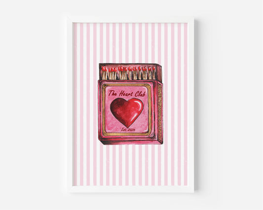 A framed art print featuring a watercolor illustration of a pink matchbox labeled 'The Heart Club' with a red heart, set against a pink and white striped background.