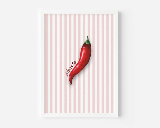 A framed wall art print featuring a single red chili pepper on a white and pale pink striped background, with the word 'picante' written in script. The print is shown in a white frame against a light gray wall.