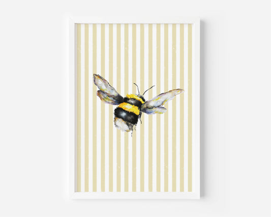 A framed art print featuring a watercolor bumblebee centered on a background of vertical cream and pale yellow stripes, set against a clean white wall.