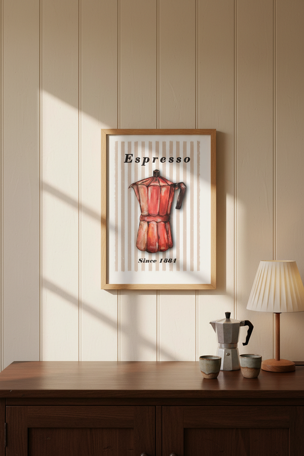 A framed art print featuring a vintage red espresso moka pot with the word 'Espresso' and 'Since 1881' on a cream background, hanging on a beige wood-paneled wall above a wooden cabinet with a lamp and cups.