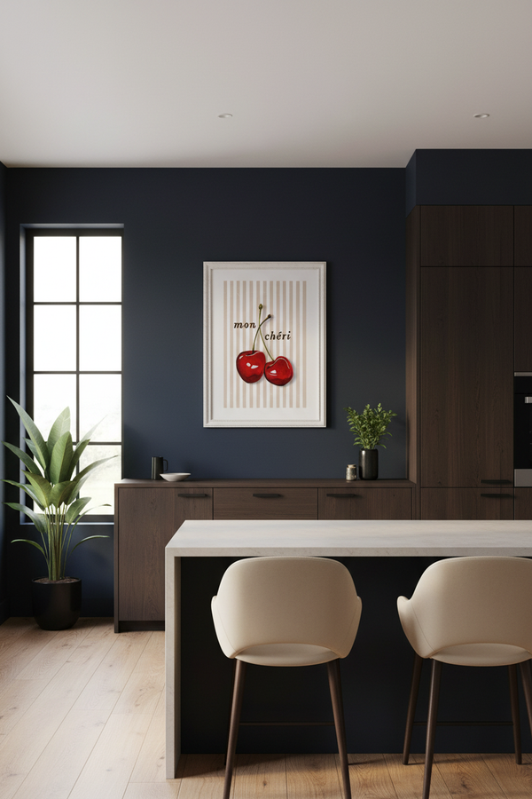 A modern kitchen interior with a dark navy blue accent wall, a white-framed cherry art print, dark wood cabinetry, a white island, and two cream bar stools.