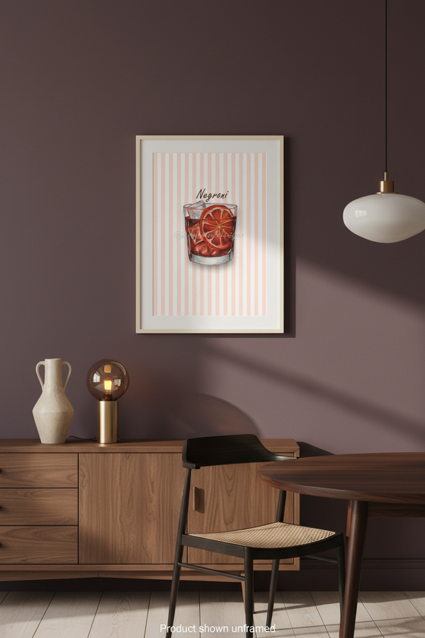 A framed art print featuring a cocktail called 'Negroni' with orange slices, displayed on a dark purple wall in a modern dining room setting.