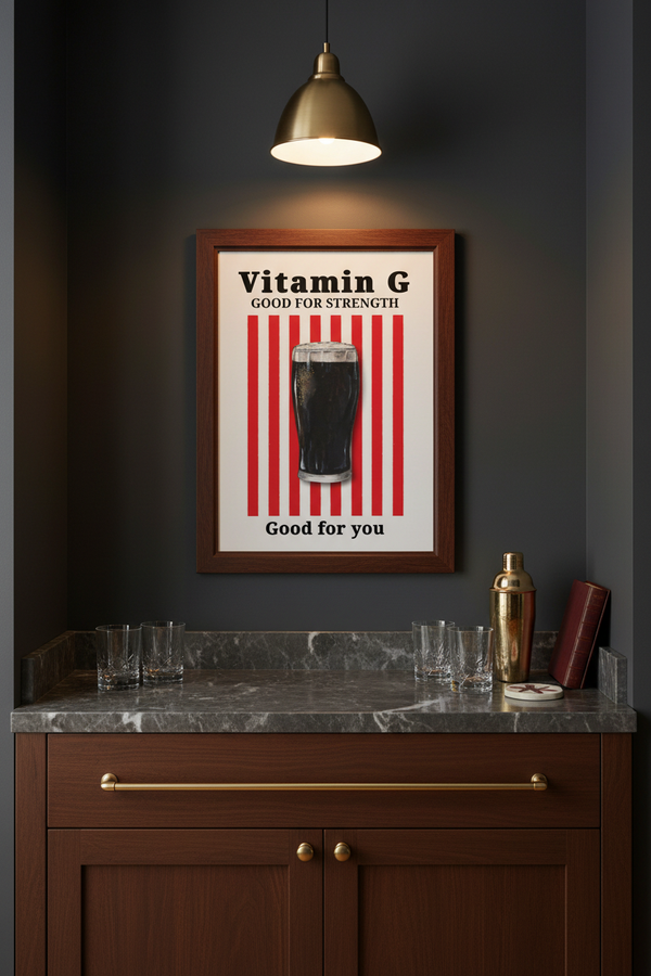 A framed vintage-style poster reading 'Vitamin G Good for Strength' with red vertical stripes and a dark glass illustration, displayed on a dark wall above a bar counter with glasses and bottles.